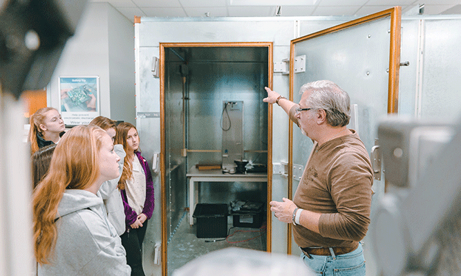 An SRC Engineer explains an anechoic chamber to high school students